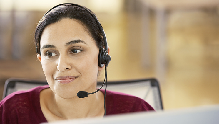 Customer service representative wearing a headset while assisting a caller.